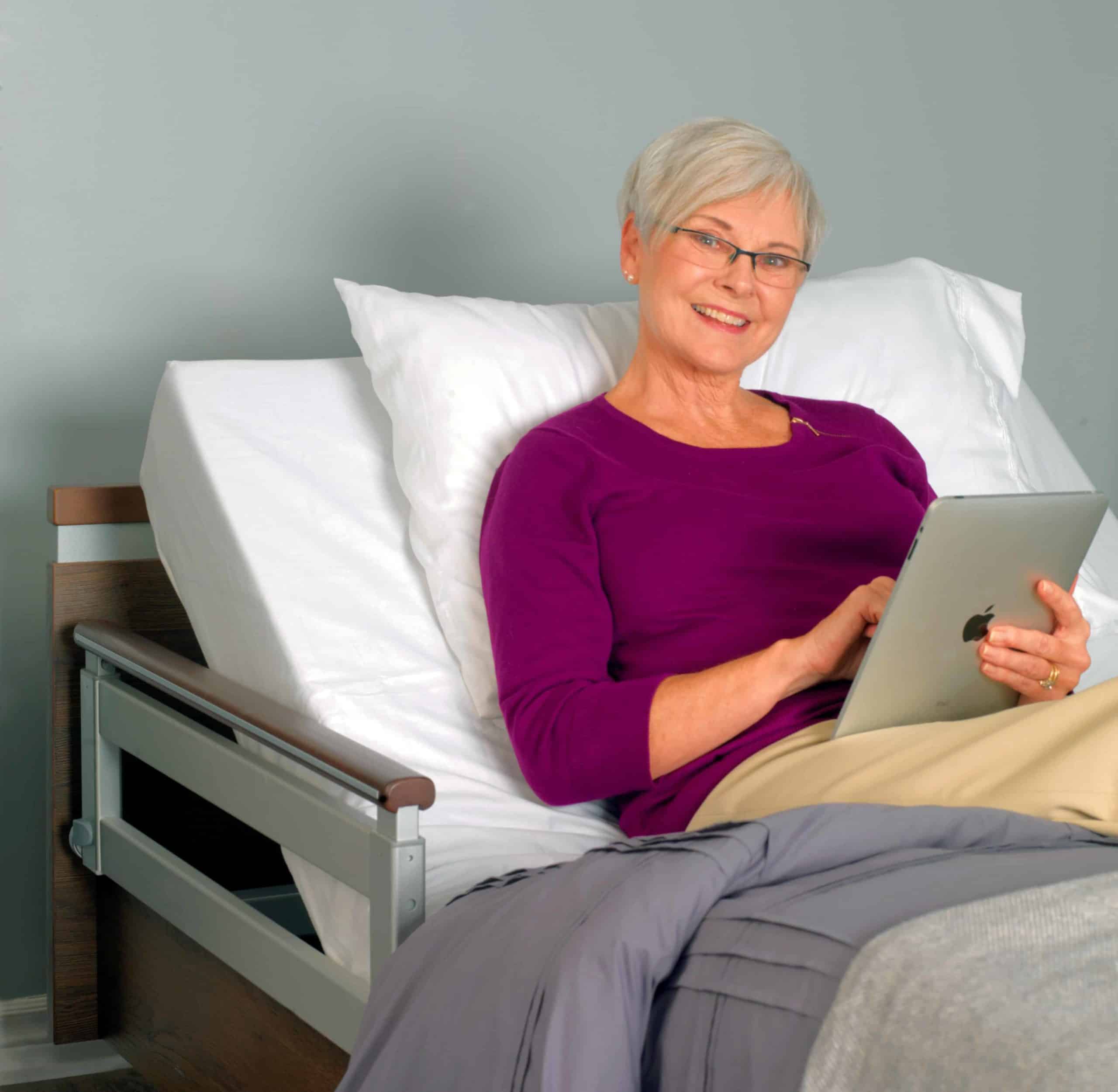 a woman sitting on a bed with a tablet.