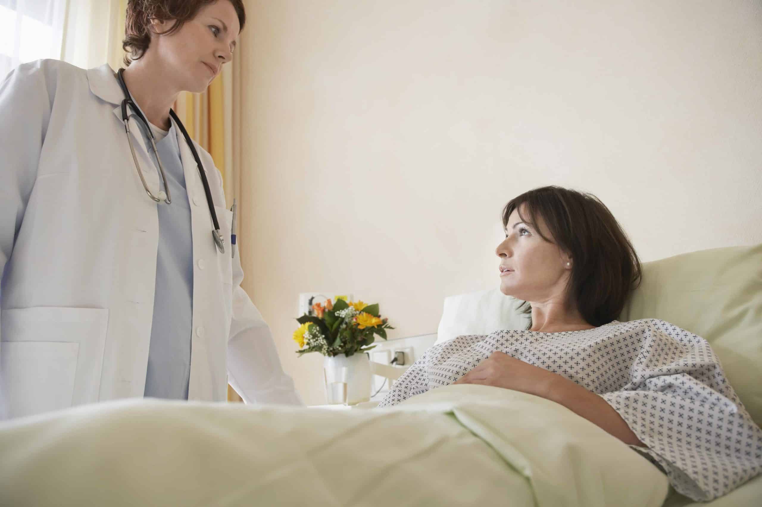 a woman in a hospital bed talking to a doctor.