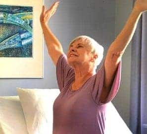 a woman in a purple shirt is holding her arms up in the air.