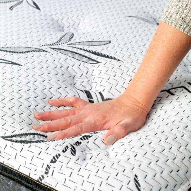 a person's hand on a mattress with a patterned cover.