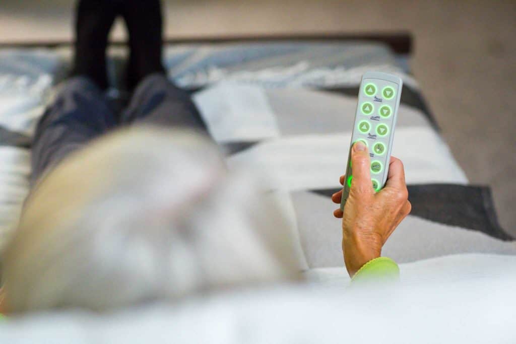 a person laying on a bed holding a remote control.