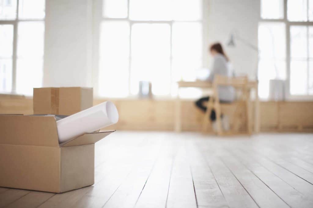 a woman sitting at a table in a room with boxes on the floor.