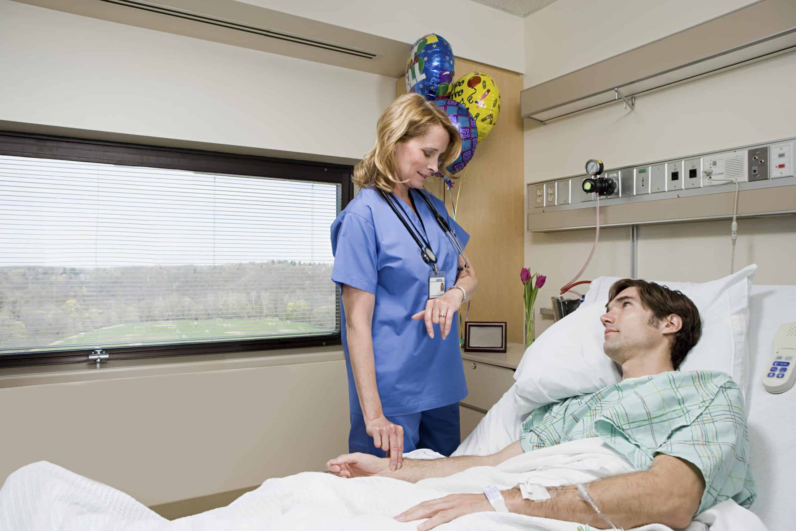 a woman standing next to a man in a hospital bed.