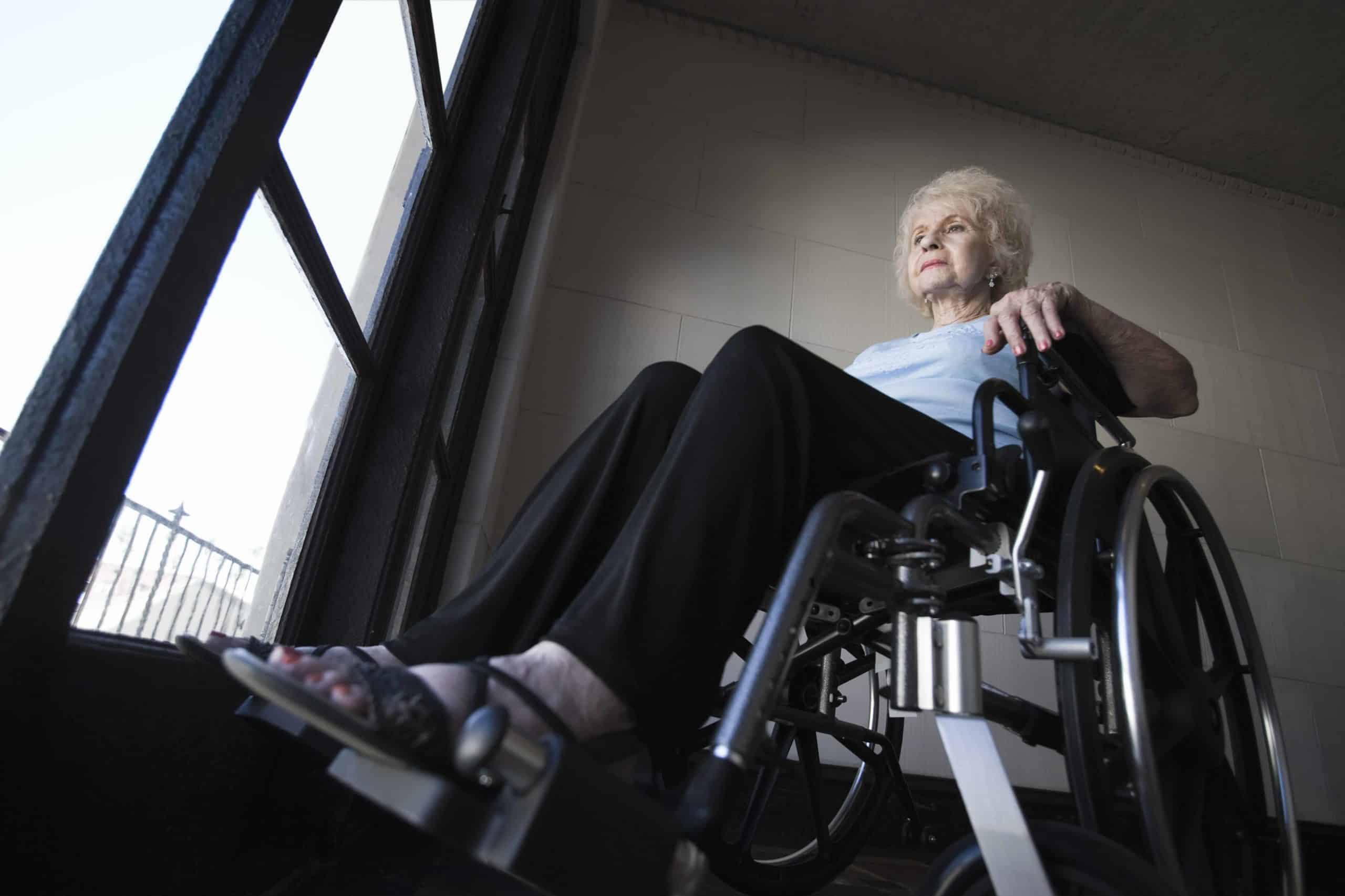 a woman in a wheel chair looking out a window.