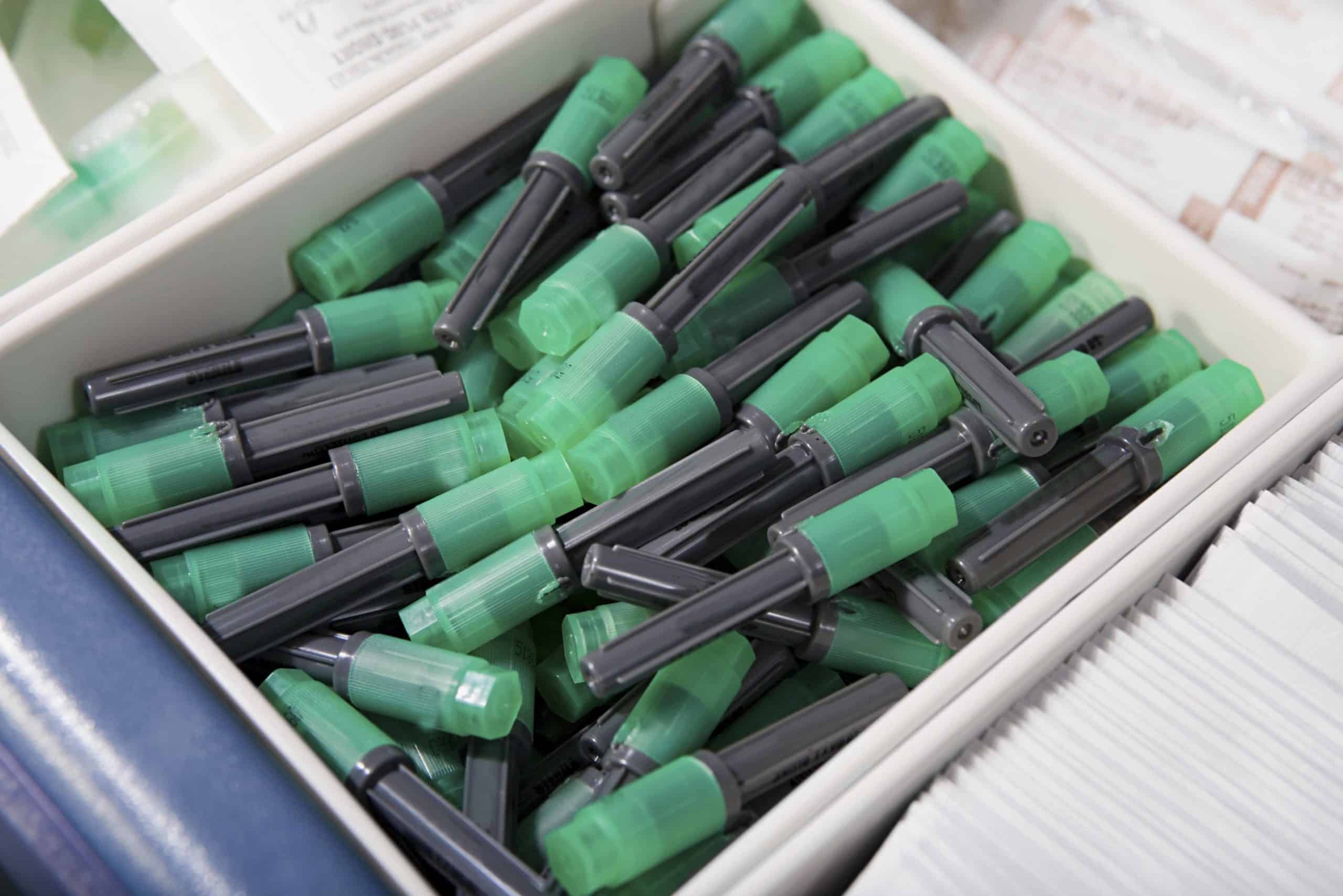 a box filled with lots of green and black markers.