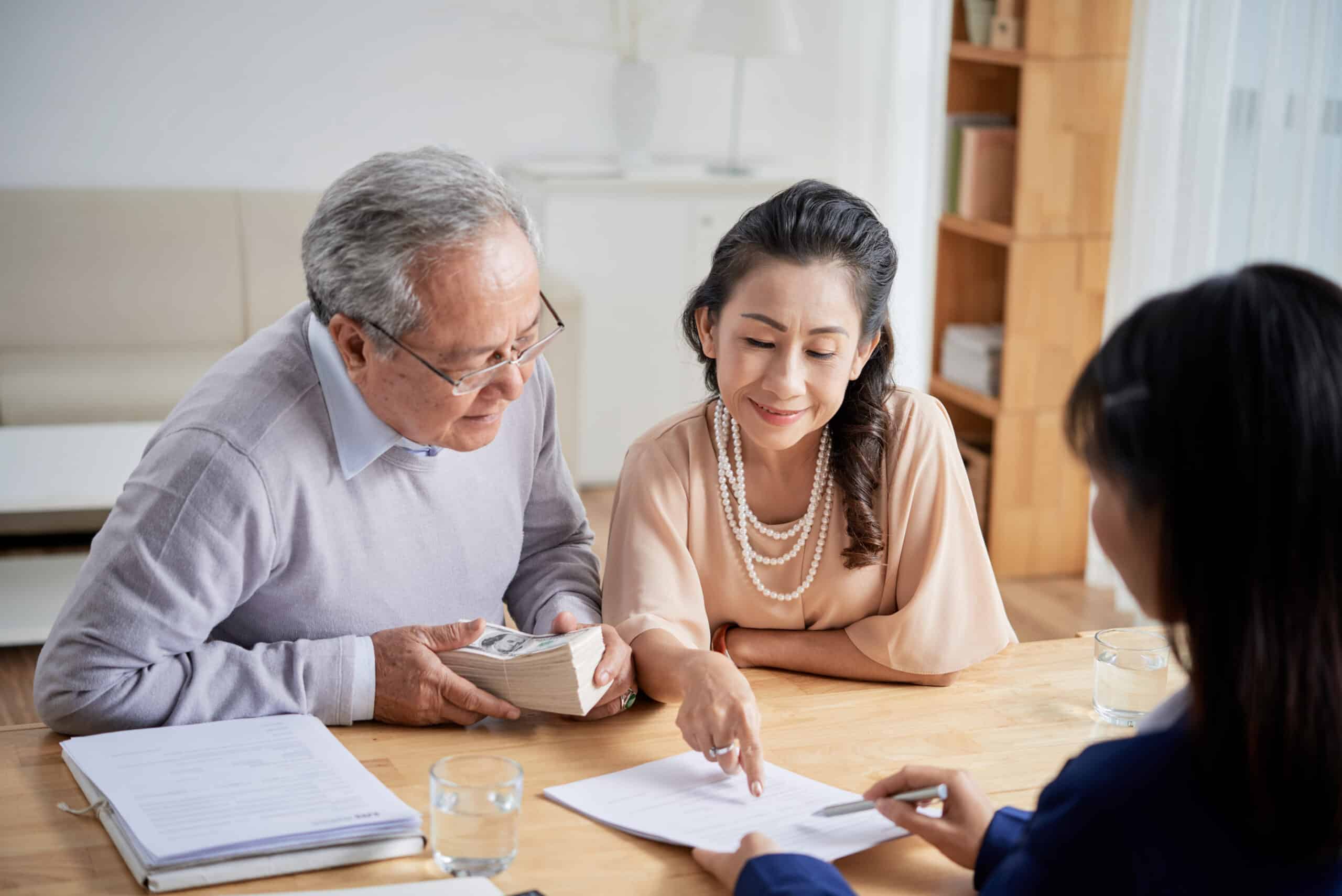 Asian couple looking at papers at a table.