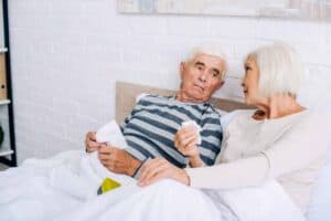 An elderly couple conversing in bed.