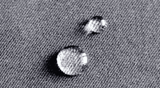 A black and white photo of water droplets on a fabric.