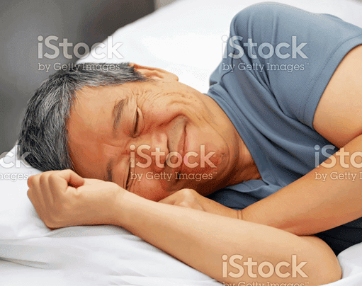 An asian man sleeping in bed stock photo.