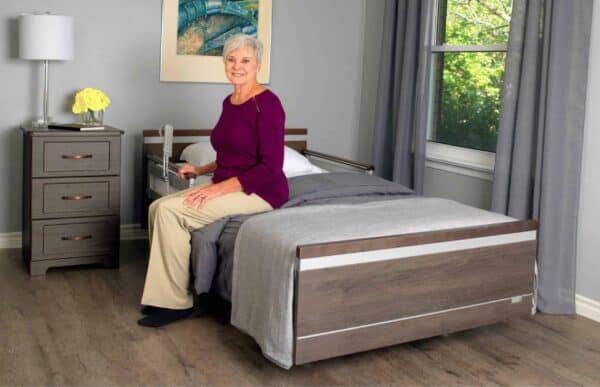 A woman sitting on a bed in a bedroom, using the Aura Premium Wide 48 Upwork.
