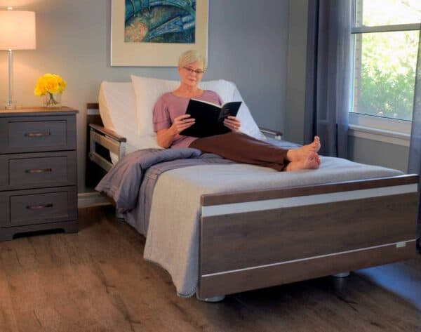 A woman reading a book on an Aura Premium Wide 48 Upwork in a hospital bed.