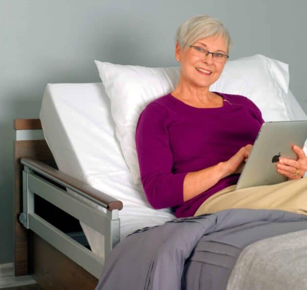 A woman sitting in a bed with an Aura Premium Wide 48 Upwork tablet.