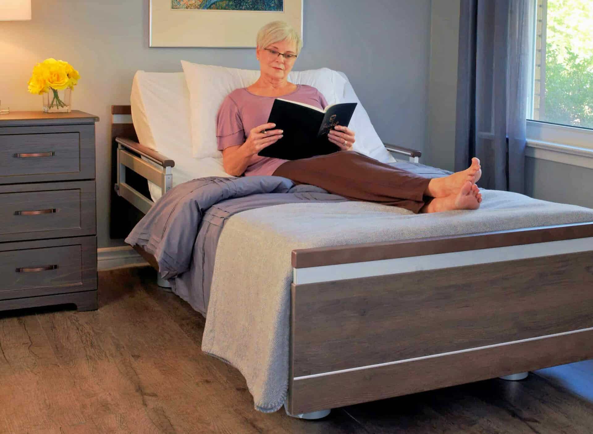 A woman is sitting on a bed reading a book.