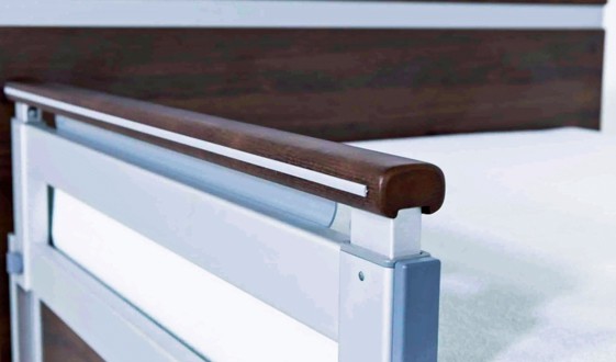 A close up of a bed with a metal rail.
