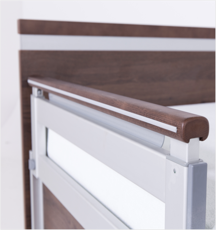 Close-up of a hospital bed headboard and side rail, featuring wood accents and metal components.