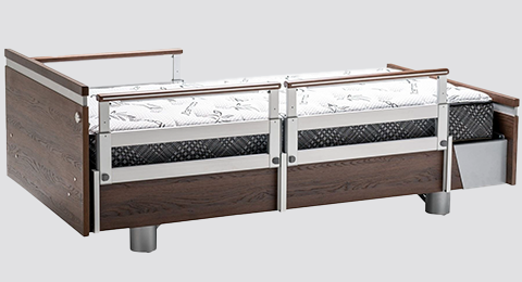 A hospital bed with side rails and a patterned mattress.