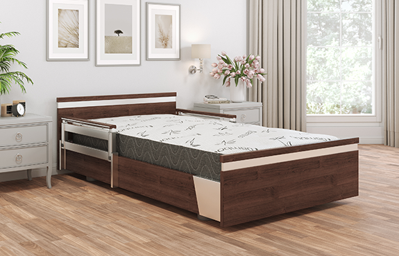 A modern hospital bed with wood accents and integrated side rails is placed in a well-lit bedroom with light-colored walls, wooden floor, and decorative artwork.