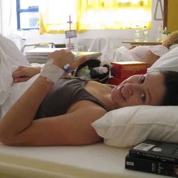 a woman laying in a hospital bed with an iv in her hand.