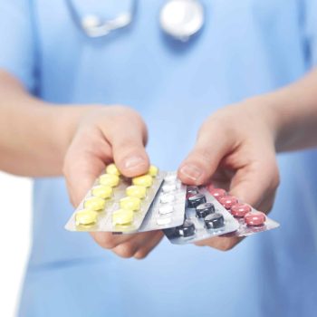 a person in a blue shirt holding a contraption and pills. a person in a blue shirt holding a contraption and pills.